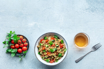 Quinoa tabbouleh salad in a bowl, a healthy dinner with tomatoes and mint, overhead flat lay shot with copy space