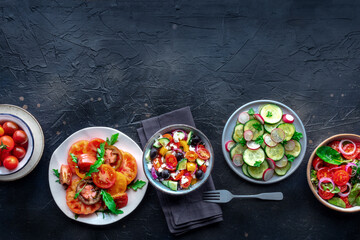 Fresh salads, overhead flat lay shot of an assortment. Variety of plates and bowls with green vegetables. Healthy food, top shot, with copy space