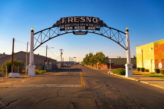 Fresno, California, USA - June 17, 2023 : Rustic archway sign reading 'Fresno - The Best Little City in the U.S.A.' over a quiet Van Ness Avenue at sunset.