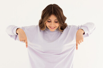 Attractive smiling woman pointing and looking down at logo, showing advertisement banner on empty space, standing in casual clothes against white background.