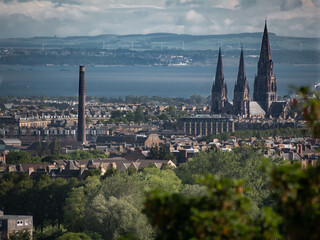 Obraz premium View of Edinburgh’s Saint Mary’s Episcopal Cathedral, with houses and trees in foreground, and the Firth of Forth and Fife in background