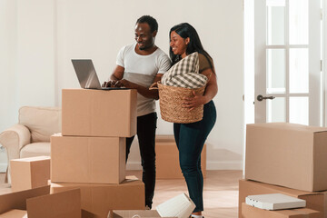 With laptop. African American couple are moving into new house