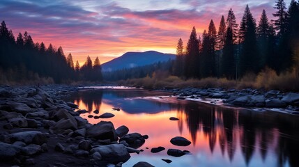 Serene mountain river at dusk with colorful sunset reflecting on the water and surrounded by dense evergreen forest.