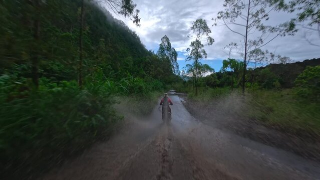 Motorcyclist on enduro motorcycle riding through puddle FPV