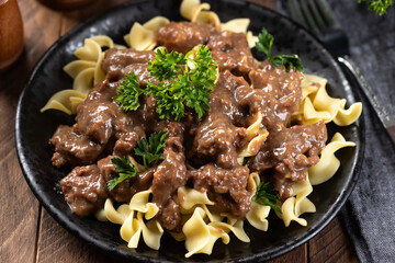 Beef stroganoff with egg noodles garnished with parsley