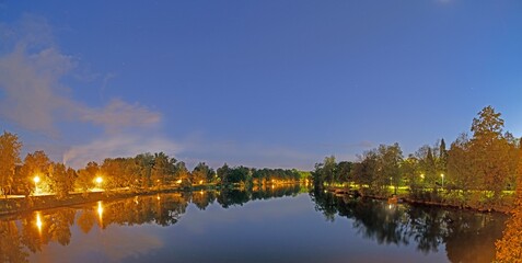 Picture over the river Danube in the evening light taken with long exposure with reflections of light and trees