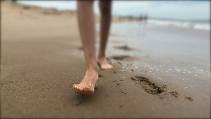Child boy feet walking at the beach closeup