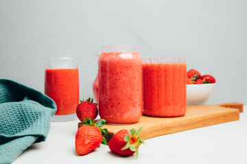 Fruit smoothie in transparent cups. Red strawberry smoothie on a concrete background. The concept of healthy eating. Front view
