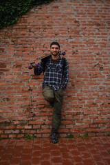 Portrait of young man with skateboard near brick wall outdoors, space for text. Active life style concept. Petrovaradin Citadel in Novi sad Serbia, Vojvodina region.