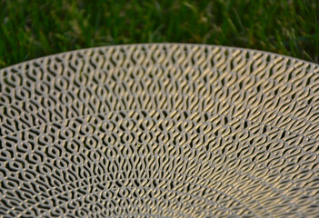 Fototapeta premium ażurowy wzór, złota podkładka na stół na tle trawnika, wzór mandala, gold table mat, mandala pattern, Decorative Doily, Gold table mat surface as background, closeup 