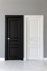 Two doors side by side, one painted black and the other white, against a neutral gray background. The stark contrast between the doors creates a striking visual effect. 