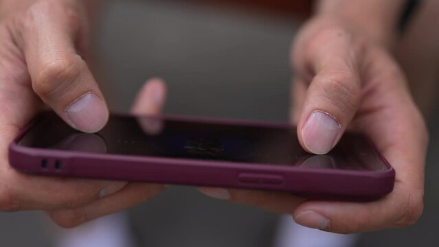 High-angle view of young man quickly tapping fingers on smartphone screen to farming new popular Hamster Combat crypto coin in phone online application. Male extract cryptocurrency using smartphone.