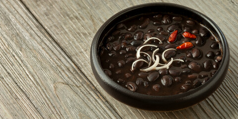 Frijoles de la Olla (Beans from the pot). Mexican homestyle black beans.Rustic wooden table. Banner with space for text.
