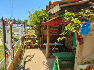 A vintage wooden pergola with fences, small tables and stools.