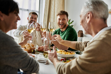 A gay couple toasts with parents during a joyous dinner gathering.