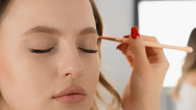 A skilled makeup artist meticulously applies eyeshadow to enhance a models eyelids, achieving a flawless look with fine detail. Closeup work and technique create a polished finish