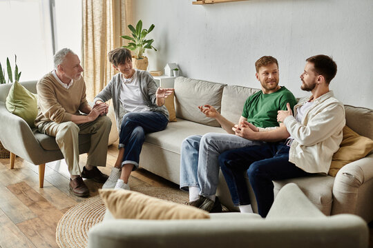 A gay couple sits on a couch while parents sit nearby, all engaging in conversation.