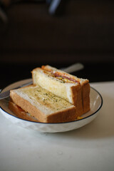 white bread filled with meat, eggs, sliced ​​vegetables and margarine on a white ceramic plate on the table