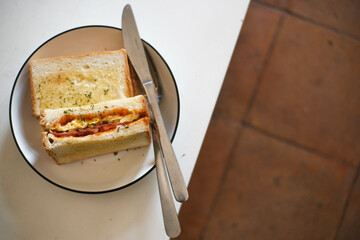 white bread with meat and egg filling spread with butter on a round plate on a minimalist table