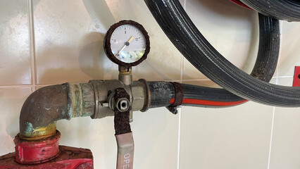 Red fire hydrant reel on a wall waiting for action