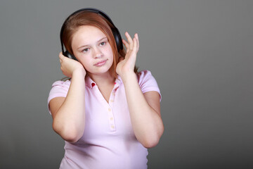A girl wearing a pink shirt and headphones