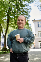 A man with inclusivity with a coffee cup walks in the city park, looking confident and content.