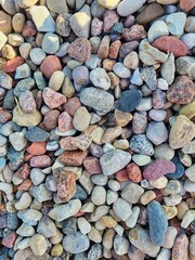 The colored stones on the shore. Pebbles on the beach, background texture. Texture, pattern of stones of different sizes. Stones and pebble background. Pavement from sea stones - texture