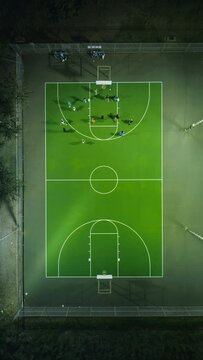 Vertical Screen: An overhead vertical video shows a night basketball game on a green court, featuring players in action under lights. The sporty scene includes a competition under nighttime lights