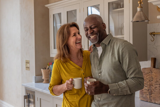 Senior carefree couple laughing together at home in the kitchen