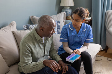 Caregiver showing senior man medication in a weekly pill box
