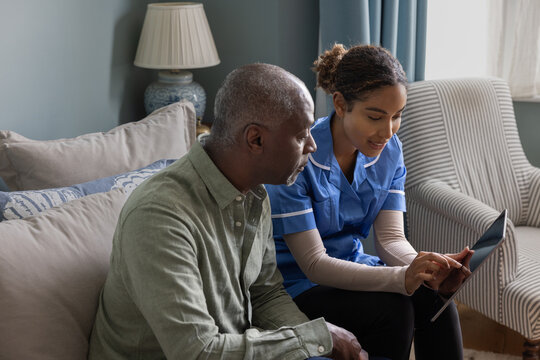 Nurse showing patient health results using a digital tablet on a home visit