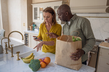 Senior couple checking grocery delivery on an app on a smartphone