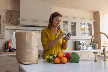 Senior woman checking grocery delivery on an app on a smartphone