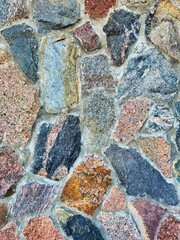 Fototapeta premium Decorative background. Stone wall background texture photo. Background texture of stone. Colorful small stones in the soil after rain. Old wall masonry, closeup. Old brick wall. Damaged stone wall