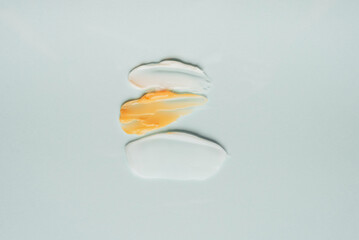 Different swatches of cosmetic products for the face and body on a blue background. Texture of skin care cosmetic product.