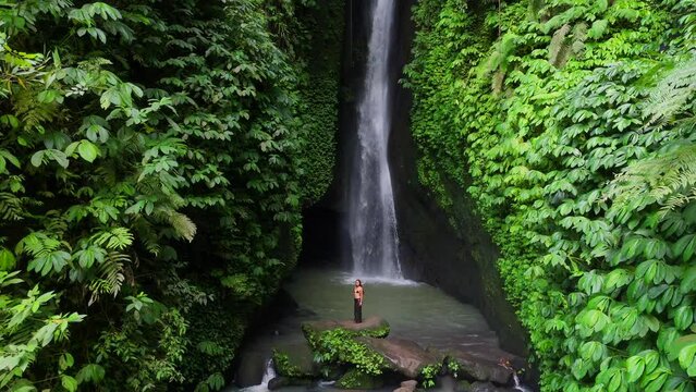An exquisite and gorgeous Asian model is elegantly posing for a charming video shoot in front of the Leke Leke waterfall in Bali - Indonesia.