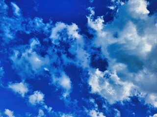 Fototapeta premium Cirrus clouds on a bright sunny day on a background of blue sky. Blue cloudy sky. Clouds in the blue sky. Dark blue sky over trees in countryside. White clouds against blue sky. Sky clouds