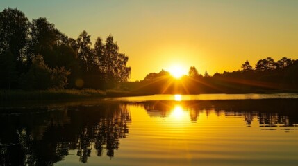 Obraz premium A serene lake reflecting the golden hues of a setting sun, with silhouettes of trees along the shoreline