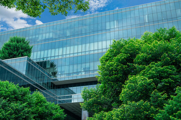 Eco-friendly building in the modern city. Sustainable glass office building with trees for reducing...