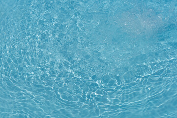 Blue water with ripples on the surface. Defocus blurred transparent blue colored clear calm water surface texture with splashes and bubbles. Water waves with shining pattern texture background.