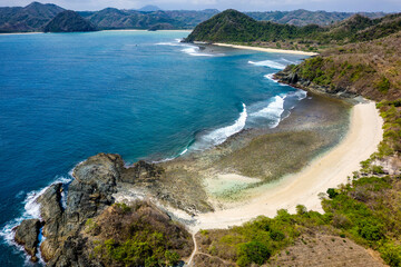 Aerial view of a small, empty tropical beach surrounded by blue ocean (Semeti Beach, Lombok)