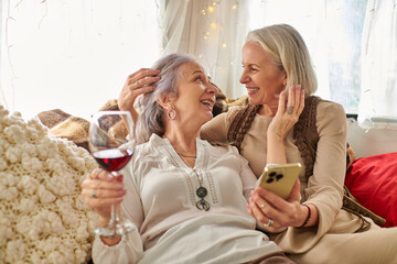 Two middle-aged women, a lesbian couple, share a glass of wine and a cozy moment inside their RV...