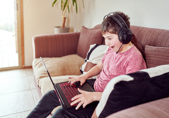 Fototapeta premium excited boy playing video games on his computer sitting in the living room of his home