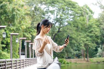 Young woman standing and listening to music at the park.