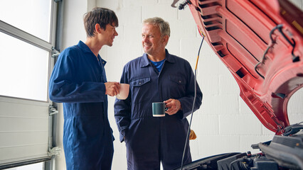 Male Car Auto Mechanic With Trainee On Coffee Break In Auto Repair Shop