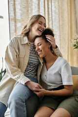 Obraz premium Two women, a lesbian couple, are laughing together at home.