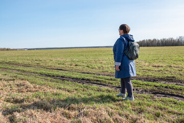 An elderly woman walks through a field.