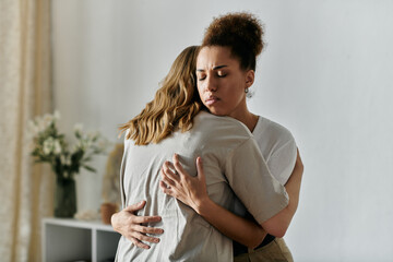 Two women in casual attire embrace each other in a loving gesture inside their home.