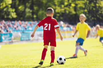 Young Boy With Soccer Ball in a Tournament Game. Two Kids Play Soccer Game on Grass Field. Happy...