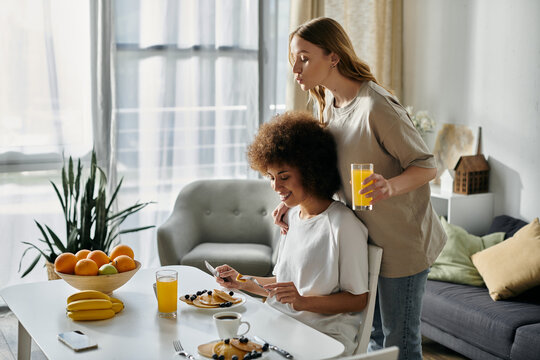 A lesbian couple shares a loving moment during breakfast at home.